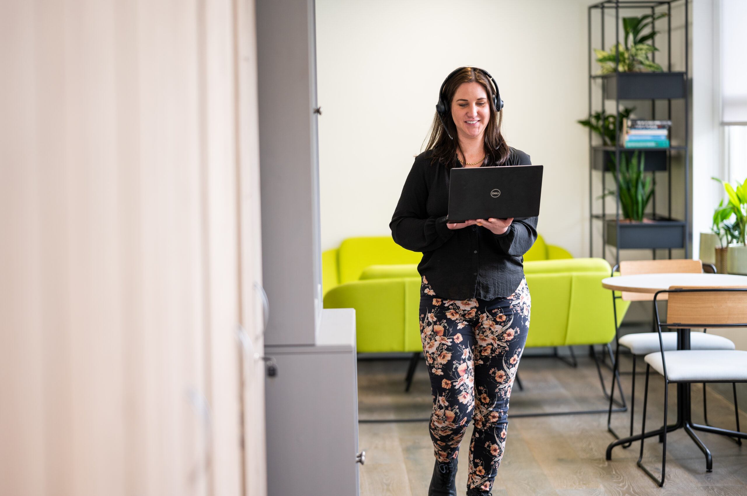 Woman walking through office with laptop