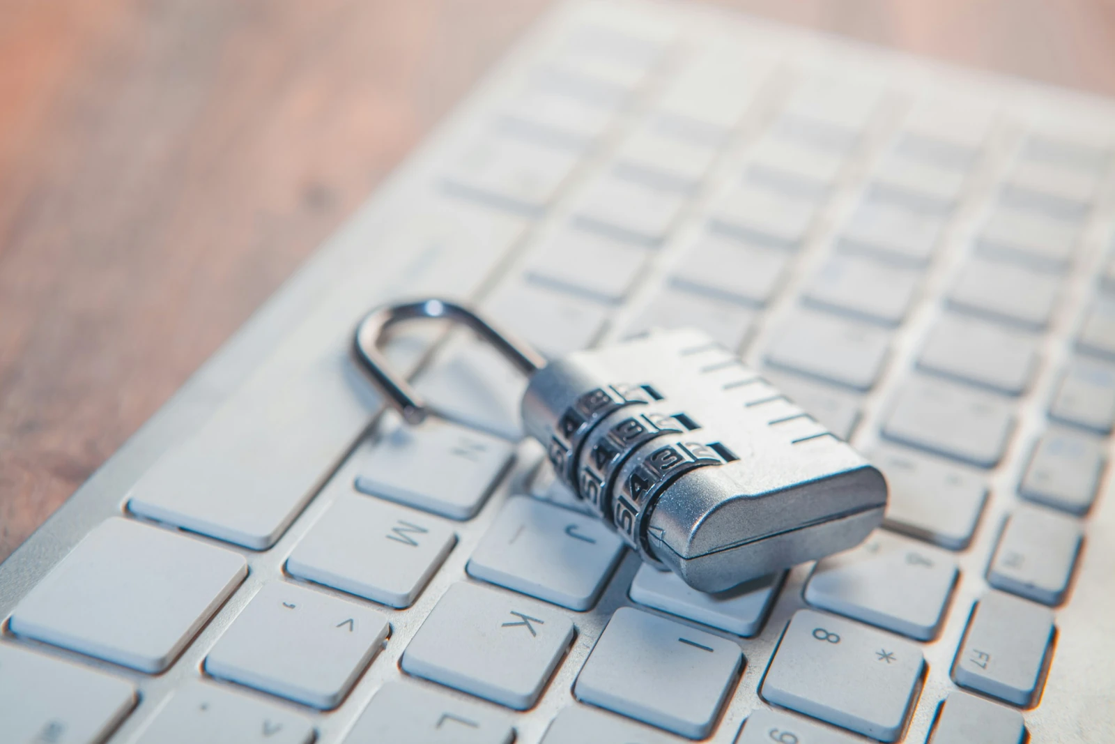 Silver combination padlock resting on a white computer keyboard, illustrating cybersecurity and digital protection.